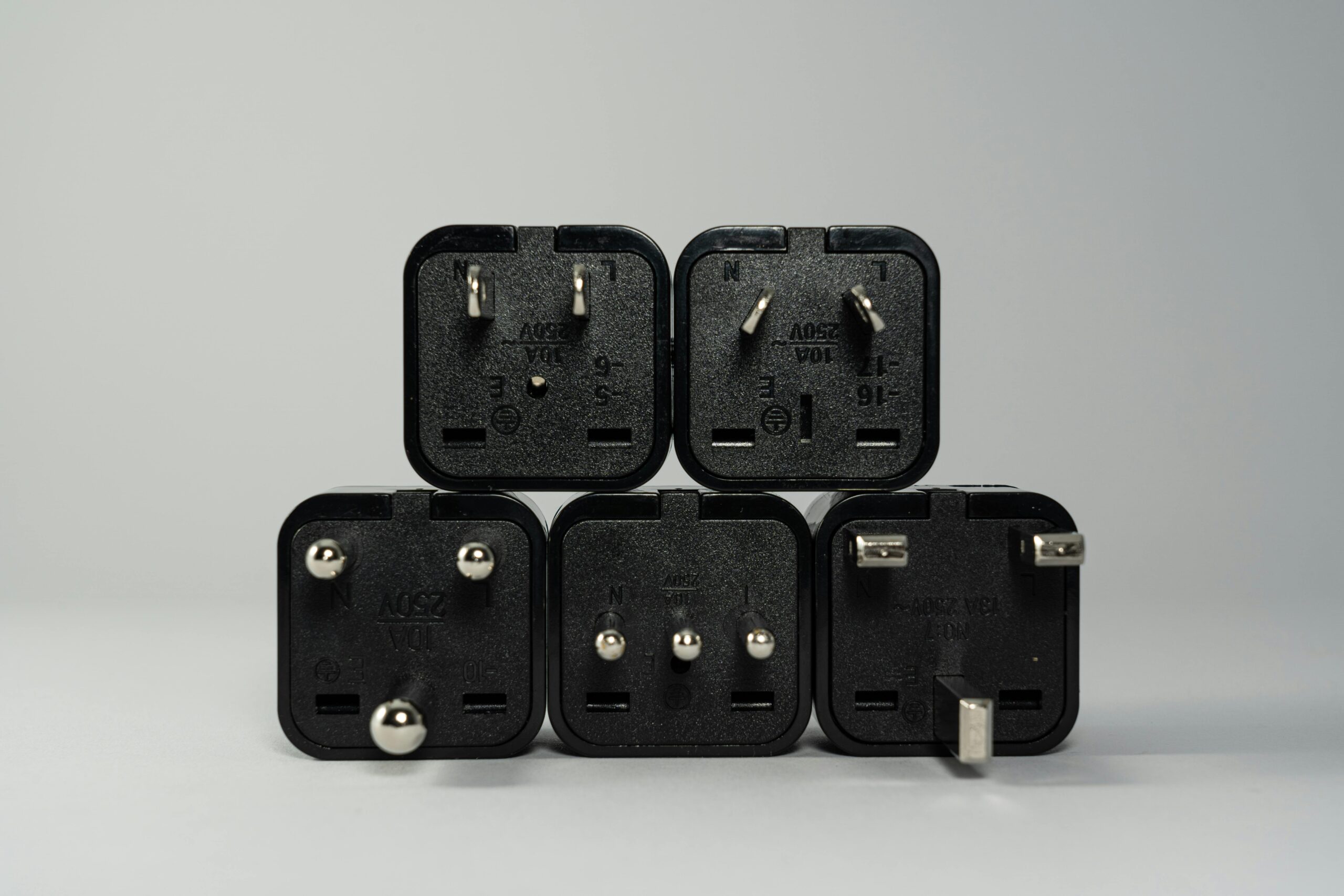A collection of various black international power plug adapters for global electronics use.